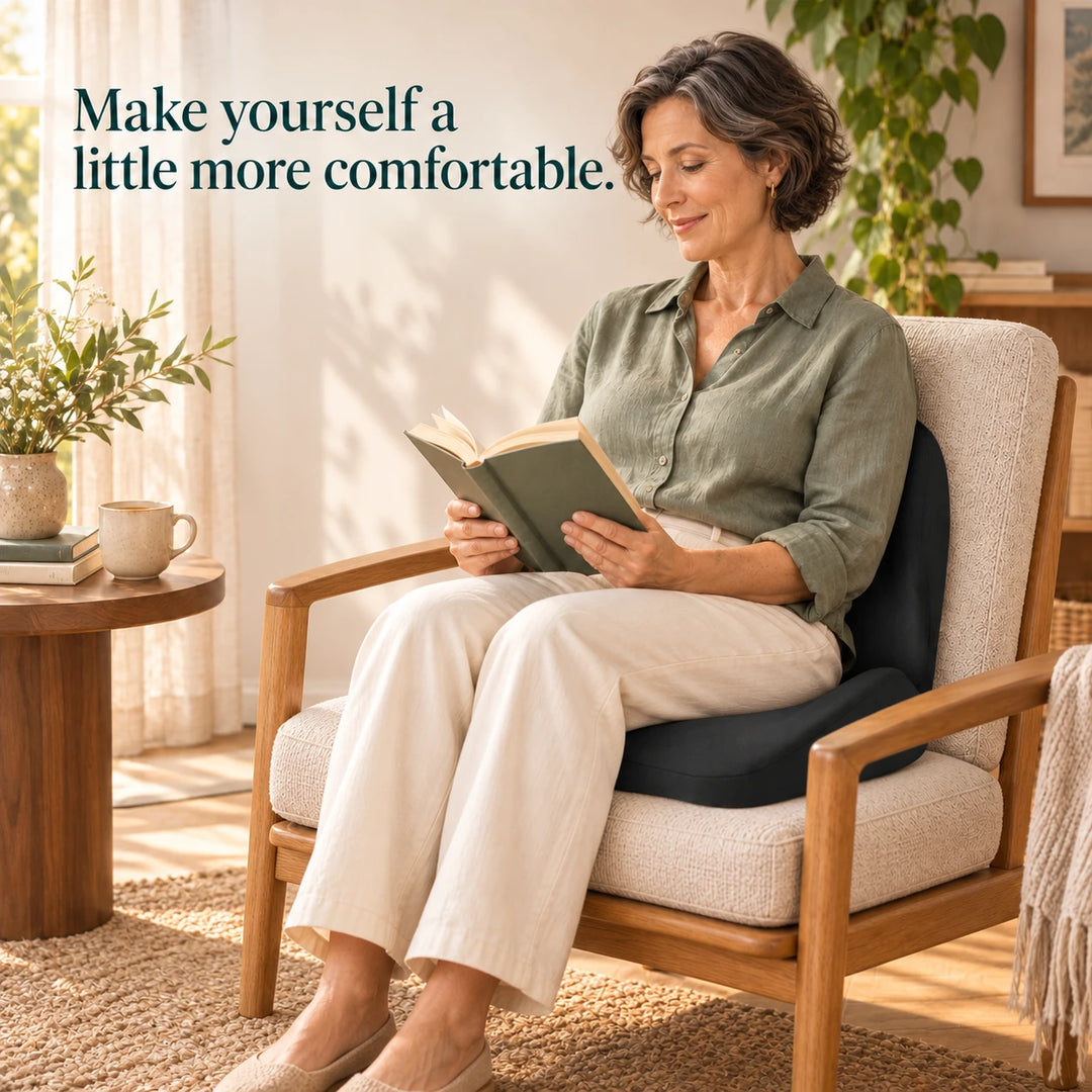 Woman seated fully on a black seat-and-back cushion while reading at home.